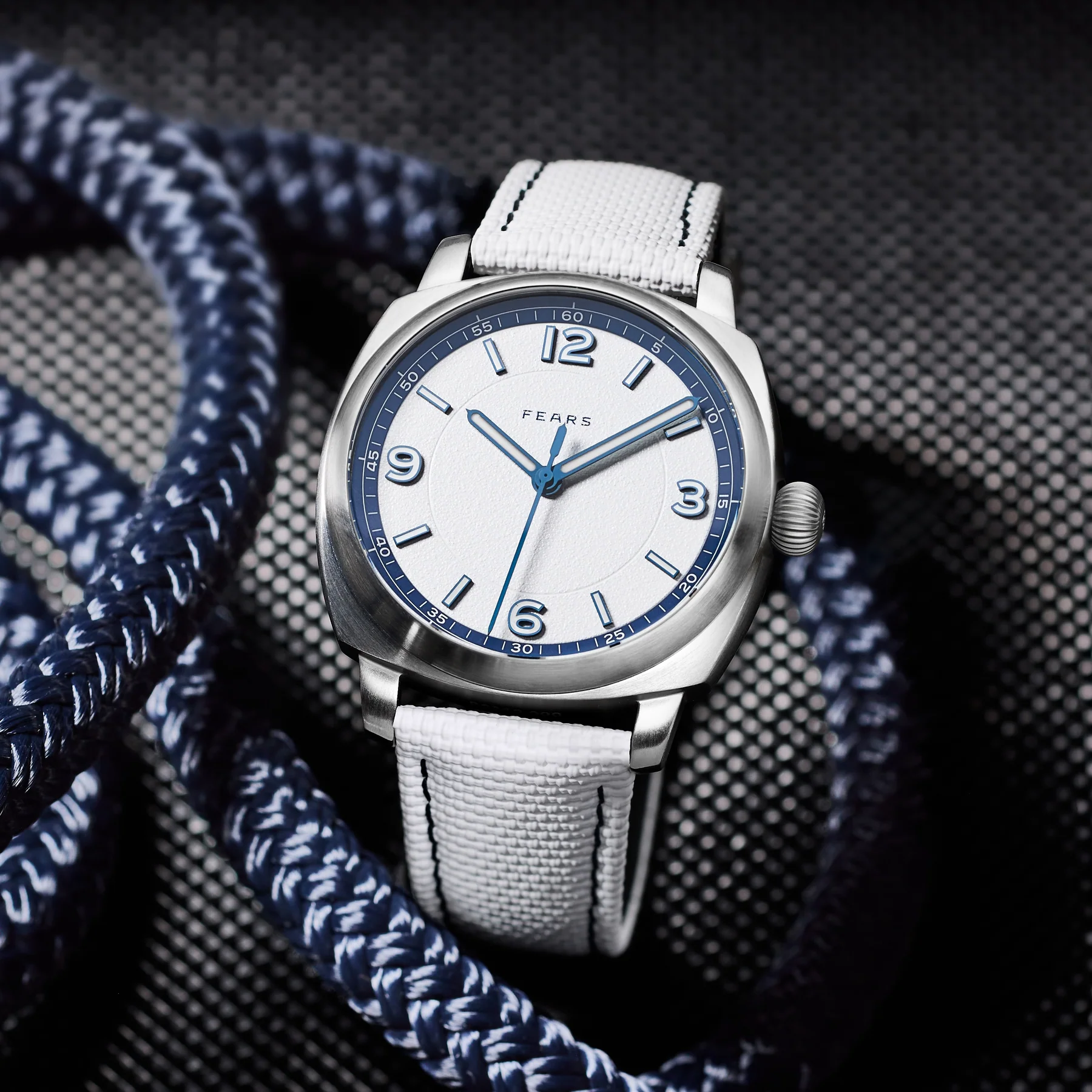 Fears Fears Brunswick 40 Helmsman wristwatch featuring a textured white dial, blue numerals and hands, cushion case, and white sailcloth strap set against coiled blue nautical rope