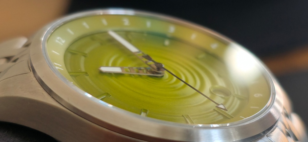 Extreme macro close-up of The Skipping Stone by Golby dial highlighting the 3D concentric ripple texture, skeletonized hands, internal rotating bezel, and domed crystal.