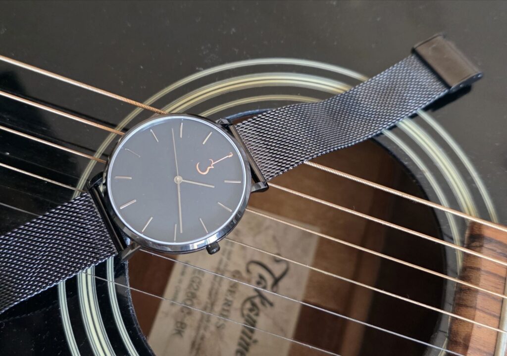 Luthier Luthier LP Black watch resting on the strings over the soundhole of an acoustic guitar.