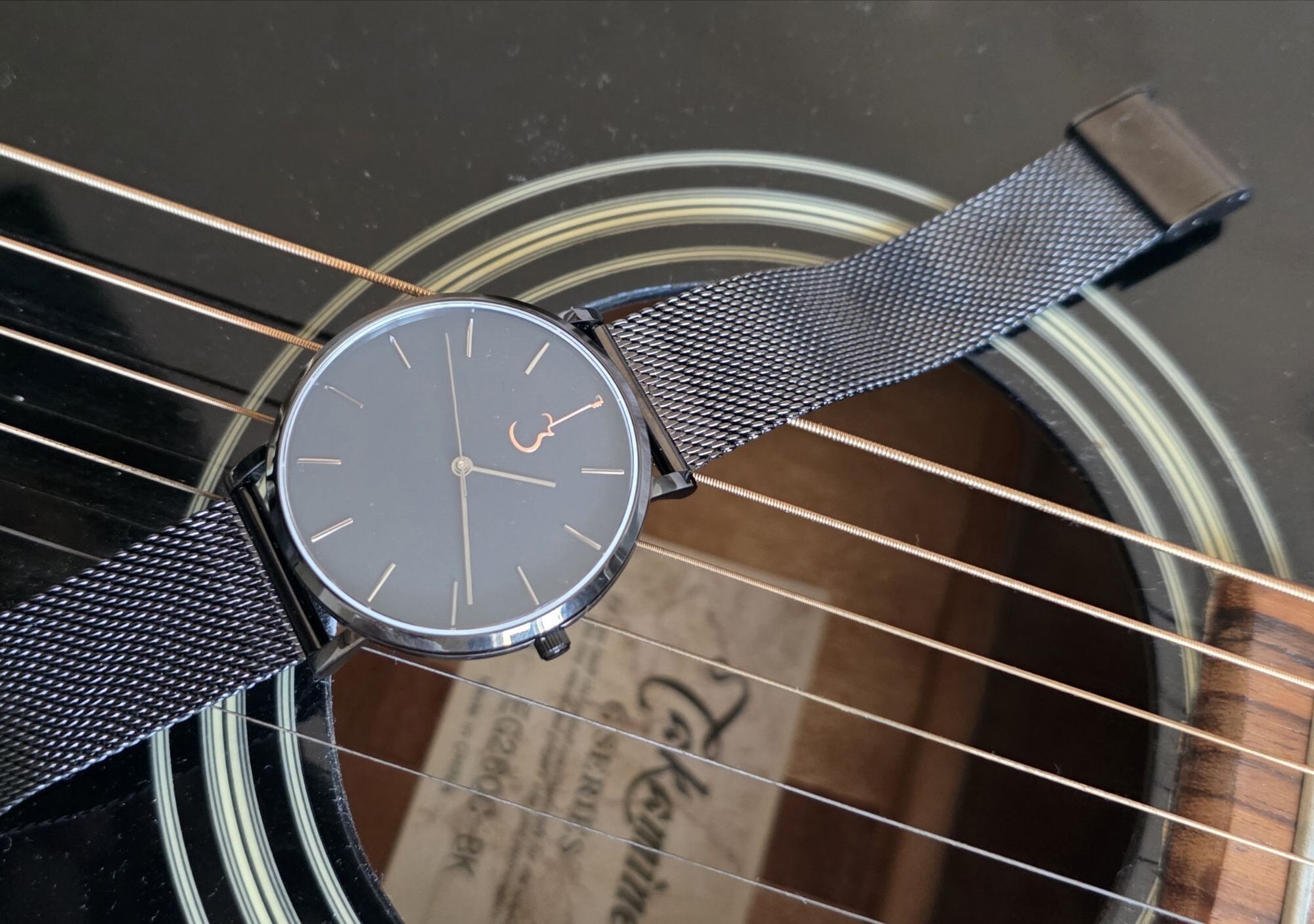 Review: Luthier LP Luthier LP Black watch resting on the strings over the soundhole of an acoustic guitar.