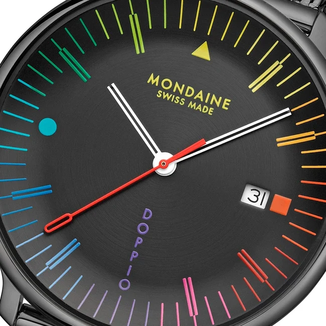 Macro close-up shot of the Mondaine Doppio watch featuring a black dial with a vibrant rainbow gradient chapter ring, yellow typography, date window, and a red second hand.