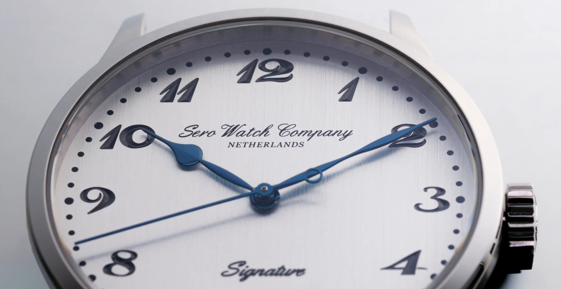 Sero Watch Company Extreme macro close-up of a Sero Watch Company Signature watch featuring a brushed silver dial, blued steel hands, raised black Breguet-style numerals, and "Netherlands" script branding.